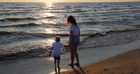 People vacation on sea. Woman and child fun on beach at sunset in summer.