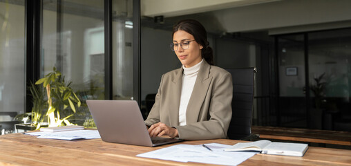 Middle age European business woman CEO using laptop application for work at table workspace in...