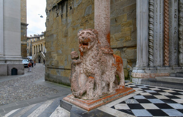 Bergamo, Italy. Lion statue front of Basilica of Santa Maria Maggiore in Citta Alta. Historical cathedral architecture of Old town.