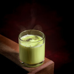 a glass of avocado juice on a table with dramatic lighting
