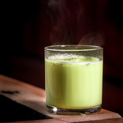 a glass of avocado juice on a table with dramatic lighting