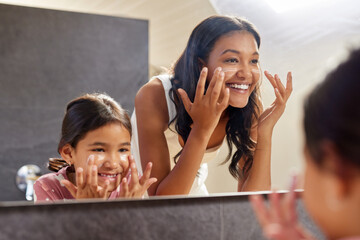 Happy mother and little daughter applying cream on face
