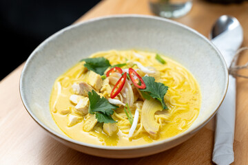 thai asian style chicken curry coconut sauce vegetable dish bistro restaurant bowl wooden table