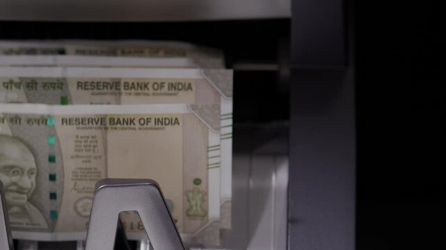 Close frontal shot of Indian five hundred rupee notes coming out of the counting machine.