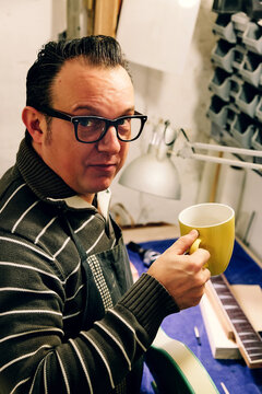 Bass guitar luthier enjoying a coffee break in his workshop