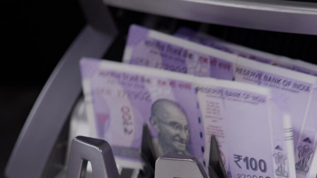Close  shot of Indian one  hundred rupee notes coming out of the counting machine.