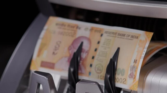 Close shot of Indian two hundred rupee notes coming out of the counting machine.