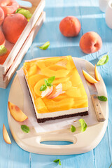 Sweet jelly peach cheesecake served on blue table.