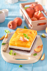 Tasty jelly peach cheesecake served on blue table.