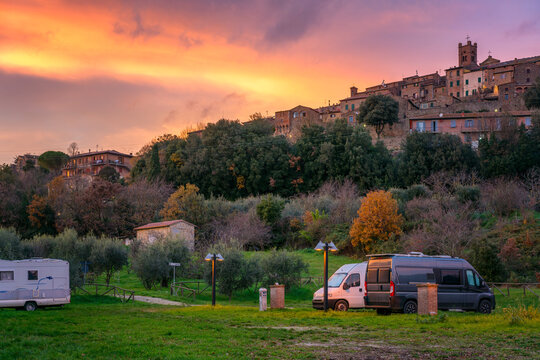 Camper vans parked near a Tuscany village at sunset