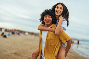 Happy Young Couple Enjoying a Piggyback Ride on a Sandy Beach
