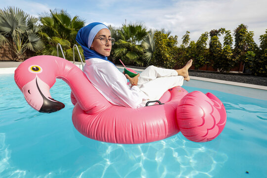 Woman relaxing on flamingo float in a sunny pool setting