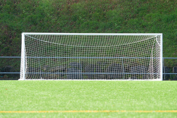 Soccer goal on a green soccer field with net and lush background