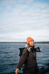 Obraz premium red-haired girl in an orange hat and coat near the sea