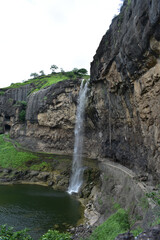 A waterfall is flowing into a lake. Kailasa Temple, Ellora Caves, India