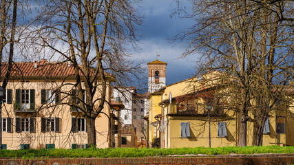 Winter in Lucca. View of charming historical center with old bell tower and city walls bare trees