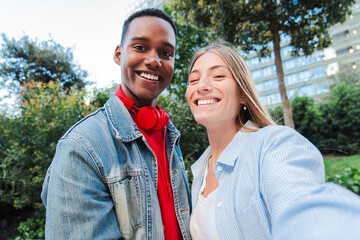 Joyful Multiracial Friends Taking a Selfie Together. Diverse Couple Capturing Moments of Happiness and Connection, Celebrating Friendship and Togetherness. Young Adult Couple Looking at Camera