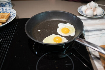 fried eggs in a frying pan on an induction hob