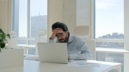 Fatigued stressful Arabian man Indian male businessman has business problem with laptop job trouble...