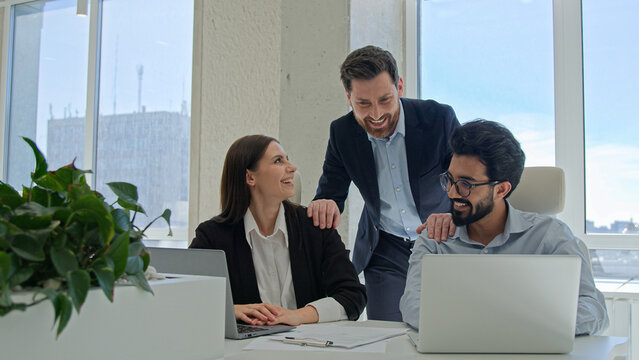 Mentor help colleagues with corporate work on laptop businessman teaching businesswoman analyze online project result discuss business development supervisor teach multiracial team managers at office