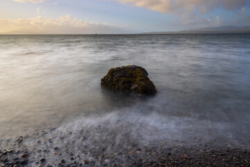 Beautiful seascape view with a solitary rock at Ganavan sands, near Oban, West Highland, Scotland, UK.