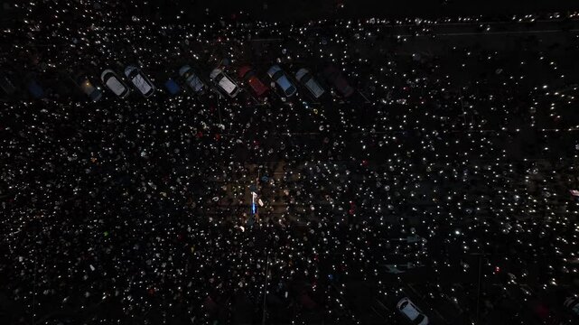 Overhead view of a vast assembly lighting up the evening with their devices amid the demonstrations.