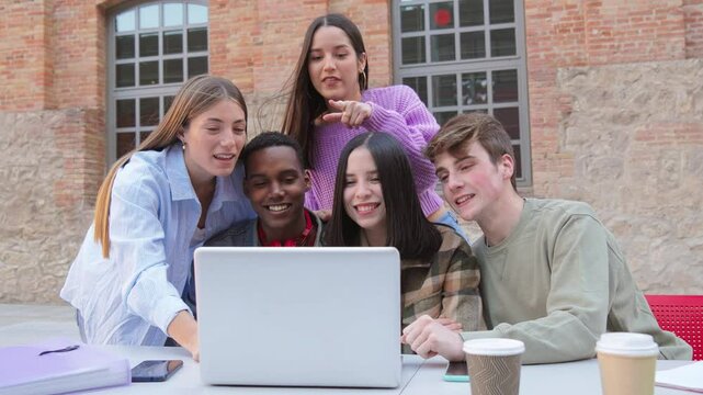 Group of enthusiastic students gathered around a laptop, engaged in collaborative study session, sharing ideas and excitement, representing teamwork and learning among teenagers at university campus