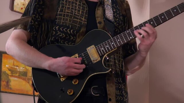 Male musician plays solo on black Gibson Nighthawk electric guitar