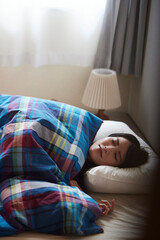 朝の寝室で睡眠をとる日本人の女性