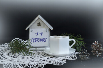 Calendar for February 11: numbers 11, name of the month February on a decorative calendar, white napkin, cup