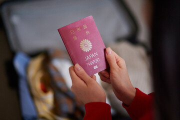 準備中のスーツケースとパスポートを持つ日本人女性の手元