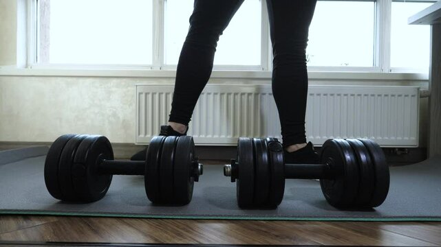 rm and leg workout with heavy dumbbells. A young man performs leg squats in slow motion