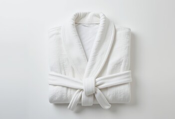 A neatly folded white bathrobe on a light background, showcasing softness and comfort, perfect for spa, home relaxation, or luxury lifestyle themes.