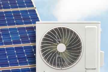 Air-source heat pump with solar panel in front of a blue sky