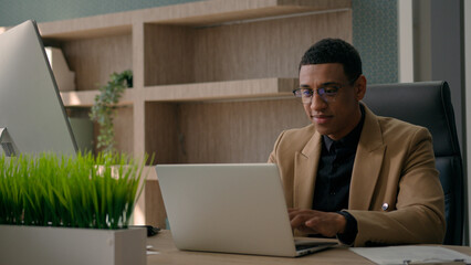 African American man working with documents at office workplace male businessman ceo manager entrepreneur employer professional executive worker research data online studying typing business project