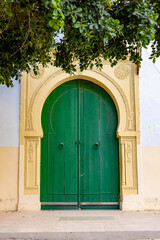 Green wooden door in a yellow colored frame of a luxurious house in Tunis, Tunesia
