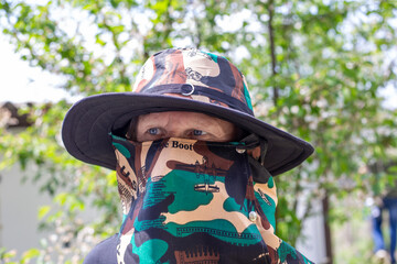 Mature man in a farmer's hat with a wide brim and a covered face.