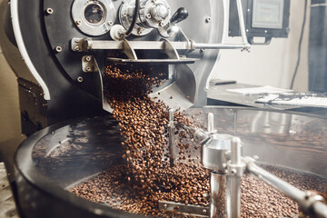 Fresh Roasted Natural Coffee Beans Cascading out of Industrial Coffee Bean Roaster Machine To the...