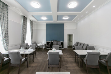 Interior of a meeting room with empty tables and chairs.