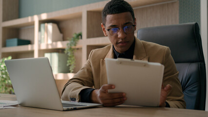 Business man African American accountant male office worker write financial data analysis plan strategy focused businessman work with laptop computer manage project study paper report signing document