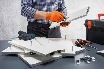 Man assembling purchased furniture. Concept of furniture assembly services.