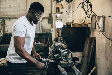 african black male worker working in heavy industry metal factory using steel lathe machine