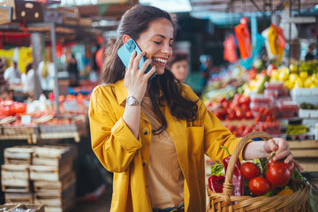 Smiling Woman Talking on Smartphone While Grocery Shopping at a Local Market