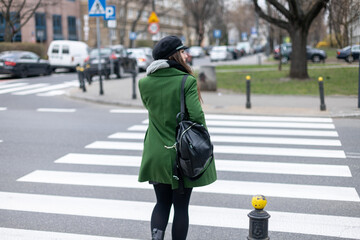 girl in green dress and cap crossing the road