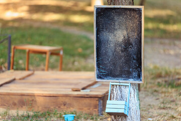 Blank chalkboard attached to tree in outdoor setting with wooden background