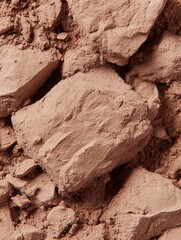 A close-up of crushed, textured powder in warm brown tones, highlighting its granular consistency and earthy appearance.