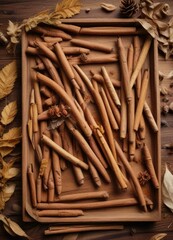 Cinnamon quills arranged in a pattern on a wooden tray with some dried leaves scattered nearby, tray, organic