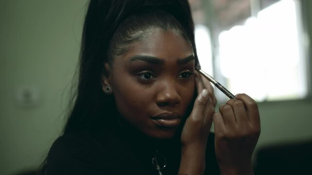 One Black Latina Young Woman Applying Makeup in Front of Mirror, Adult 20s Girl of African Descent Getting Ready to Go Out