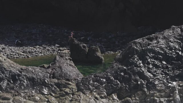 Massive waves pummeling volcanic shoreline of La Palma, lone silhouette of a girl sitting on a rock, capturing dramatic seascape's primal force and windswept intensity