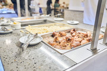 An event in a restaurant with a healthy buffet. Delicious dishes for a late dinner on plates. The chicken tongs are next to the metal containers. High quality photo